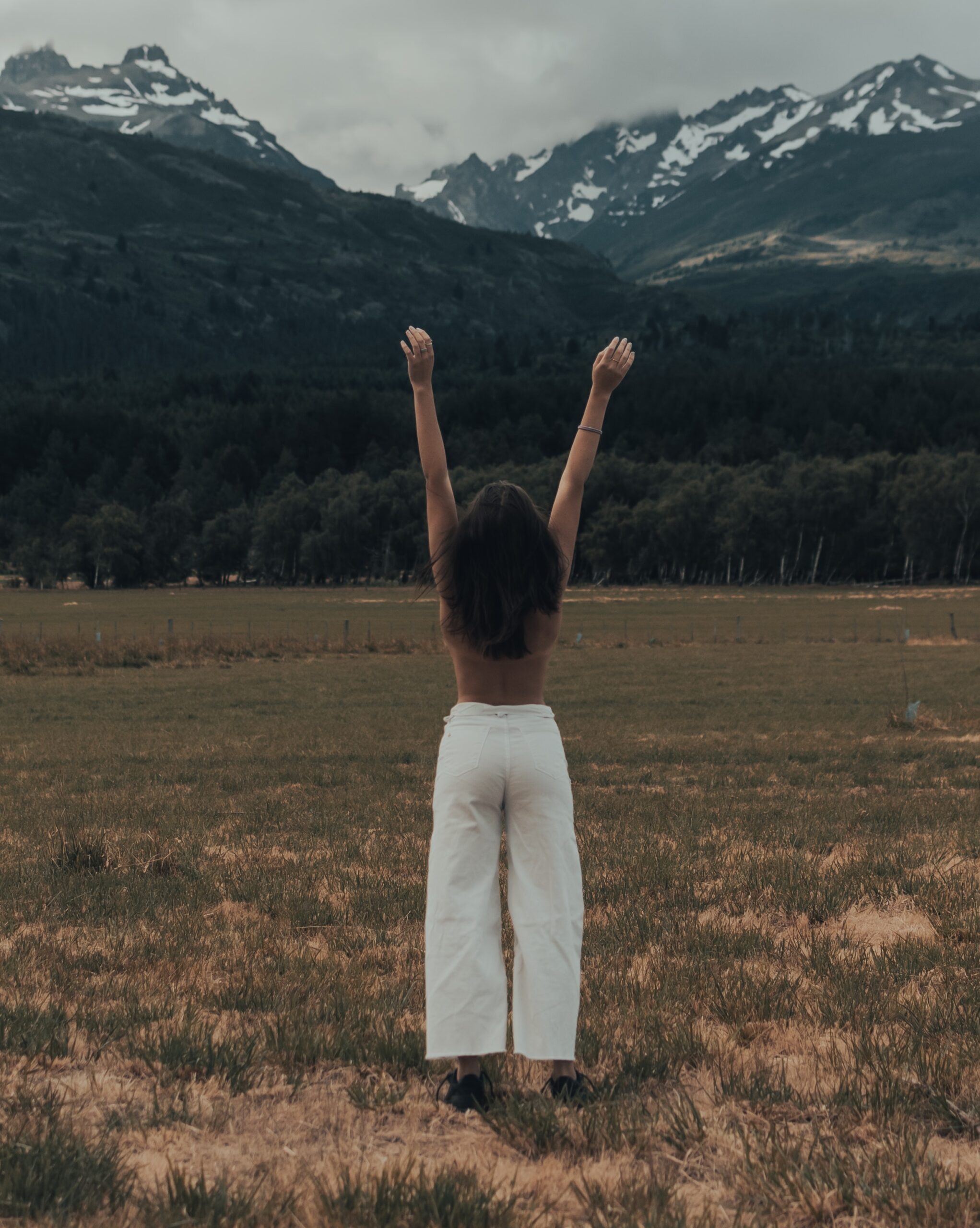 Woman looking at the mountains with her hands raised in the air